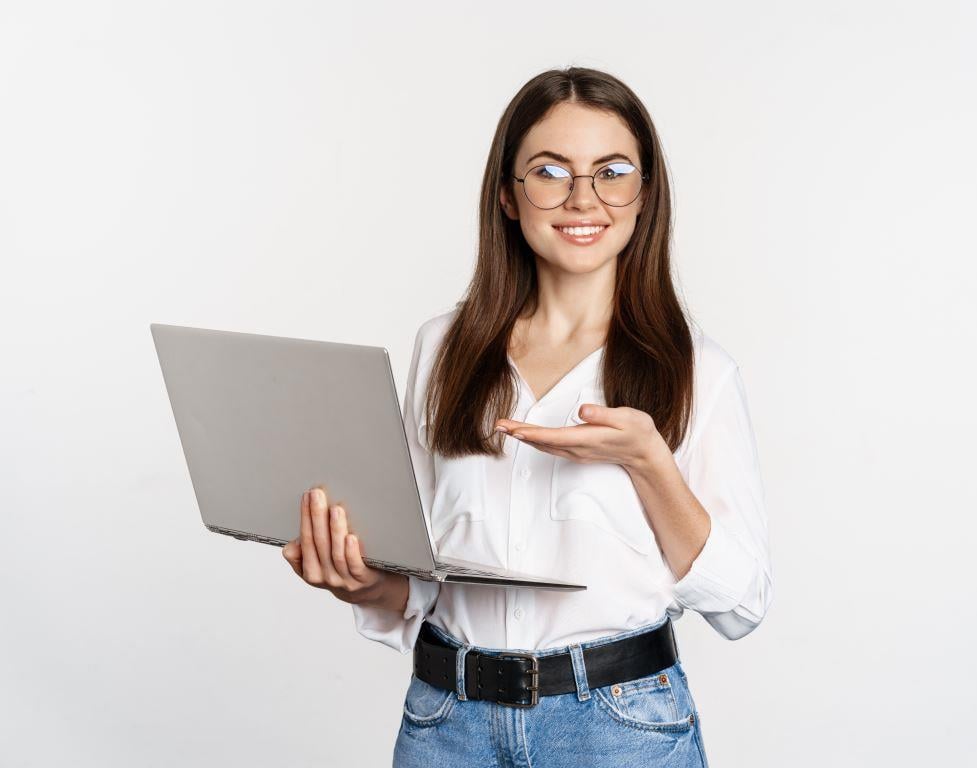 portrait-woman-glasses-holding-laptop-pointing-screen-showing-her-work-computer-standing 1